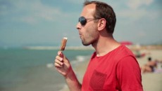 stock-footage-happy-young-man-eating-ice-cream-on-the-beach